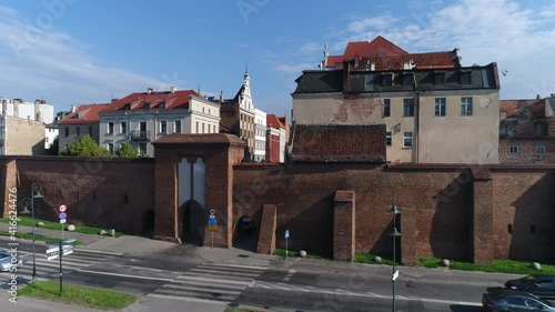 The walls of the old town in Toruń and historic tenement houses with red roofs. Beautiful sunny and summer day with a blue sky.