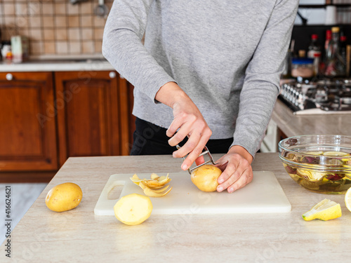 Woman peeling potatoes. Preparation of a vegan recipe in a wood-burning kitchen