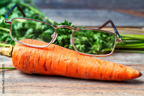 Carrots and glasses on a wooden table. Effect of carrots on human eyesight
