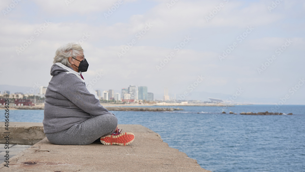 Mujer senior contempla el mar esperando que el futuro sea mejor calma meditación serenidad ciudad mar Barcelona