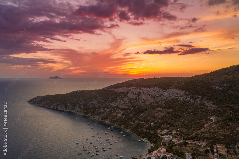Aerial drone shot of sunset burning sky clouds over Komiza town on Vis Island in Croatia Summer