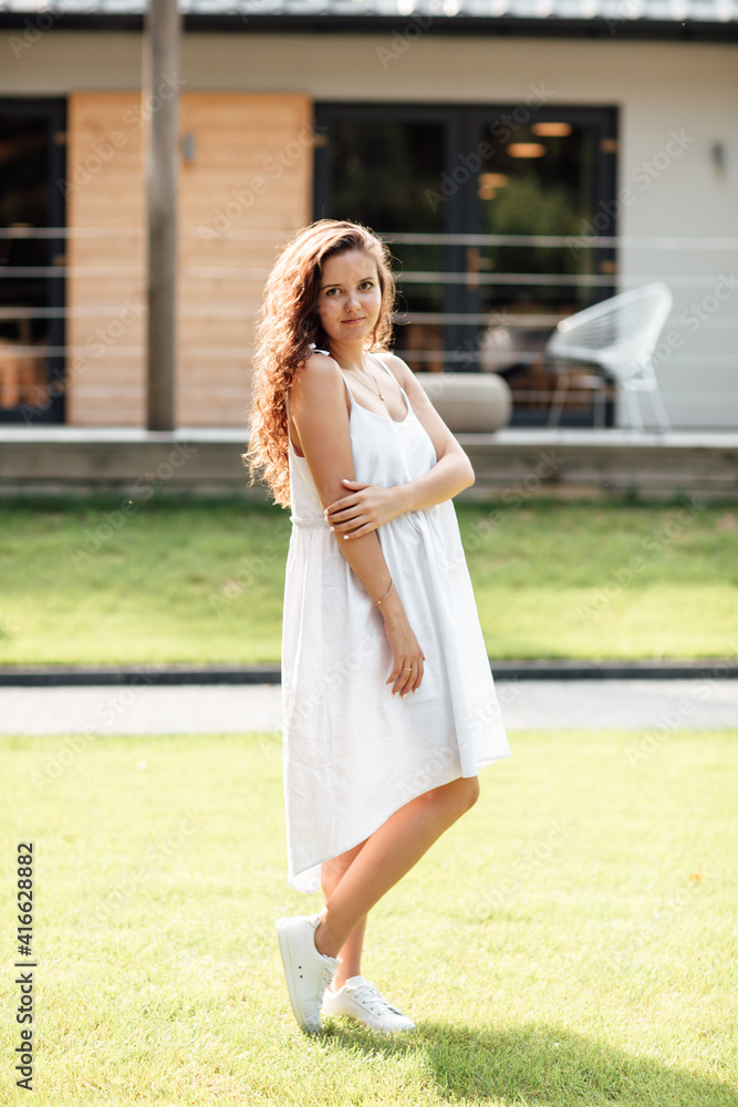 Portrait of a young beautiful brunette girl with long curly hair in the street near a summer terrace cafe Portrait of a young beautiful brunette girl with long curly hair in the street near a summer terrace cafe