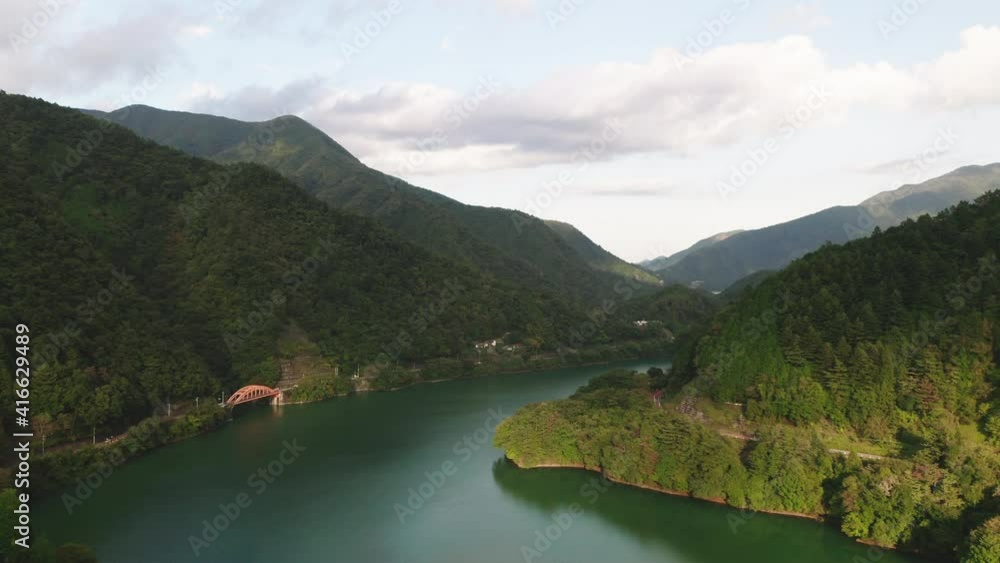 Calm Waters Of Lake Okutama With Mugiyama Bridge And Green Mountains On A Sunny Day In Okutama, Japan. - aerial Calm Waters Of Lake Okutama With Mugiyama Bridge And Green Mountains On A Sunny Day In Okutama, Japan. - aerial