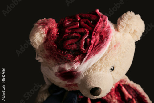 bear on a gray background close-up with a broken head. brains are visible. blood. halloween concept. horror toy