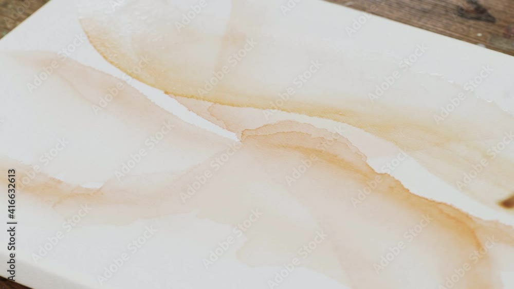 Close up of male artist paints an abstract picture, he distribute an orange paint with paintbrush Close up of male artist paints an abstract picture, he distribute an orange paint with paintbrush
