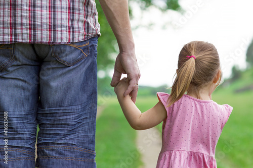 the parent holds the hand of a small child