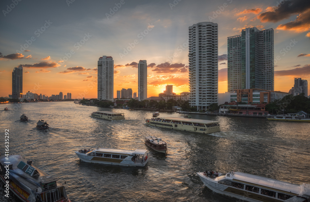Busy Chao Phraya River with Passenger Boats and Skyscrapers at Sunset as Seen from Taksin Bridge in Bangkok, Thailand