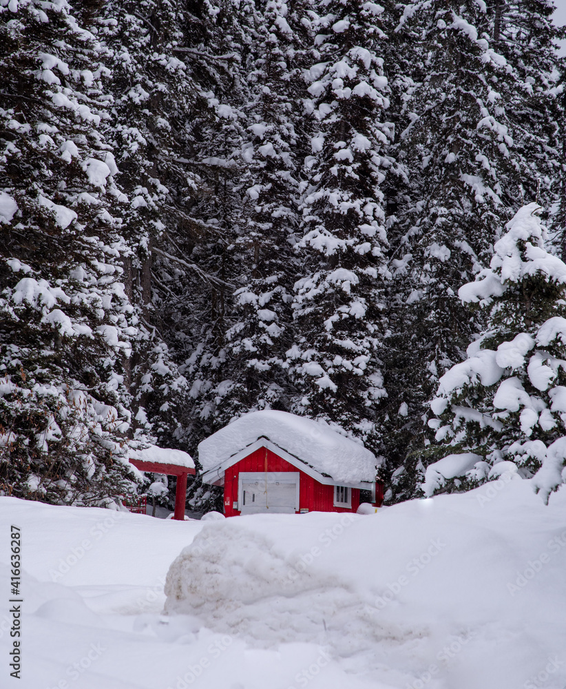 A red house or a cabin covered in snow near lake Louise. The Canadian winter landscape in Banff National park, rocky mountain. 