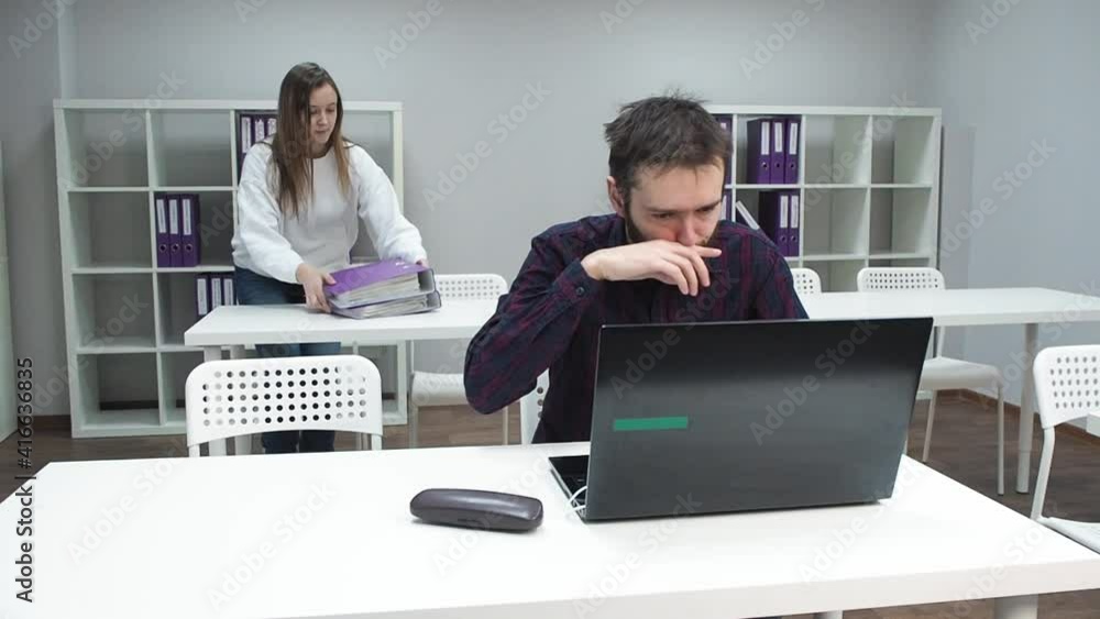Young man without Covid-19 face mask sneezing in office and colleague scared and running away from infected male. Coronavirus fear and panic concept. Young man without Covid-19 face mask sneezing in office and colleague scared and running away from infected male. Coronavirus fear and panic concept.
