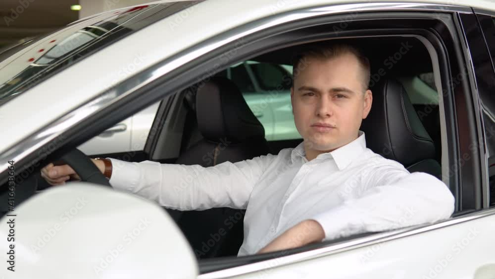 Portrait of a young confident man sitting in a new car at a car dealership Portrait of a young confident man sitting in a new car at a car dealership