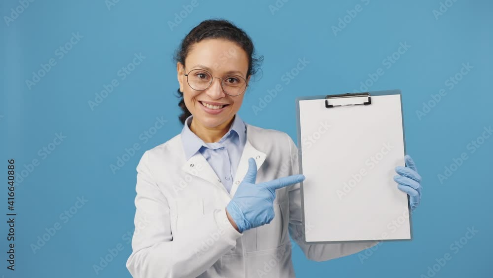 Medical prescription. Cheerful woman doctor showing blank clipboard and smiling to camera, blue background, copy space Medical prescription. Cheerful woman doctor showing blank clipboard and smiling to camera, blue background, copy space