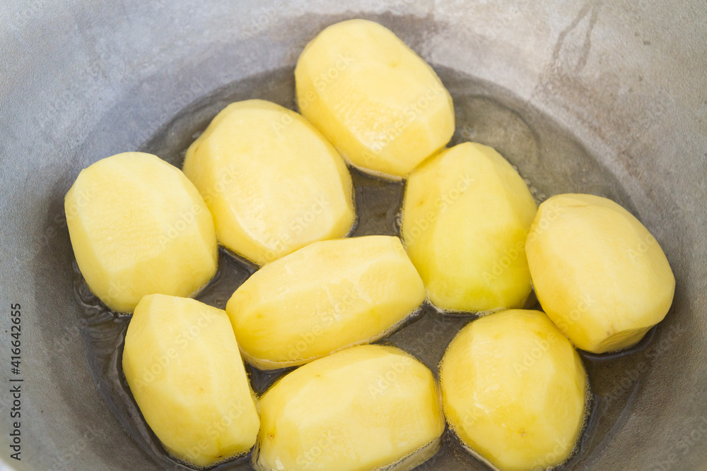 Golden potatoes are fried in boiling oil in a cauldron