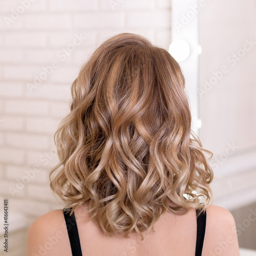 Photos Female back with short, curly, natural blonde hair in hairdressing salon