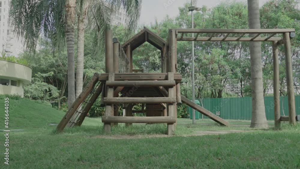 Wooden playground toy inside a park full of nature, with grass and trees Wooden playground toy inside a park full of nature, with grass and trees