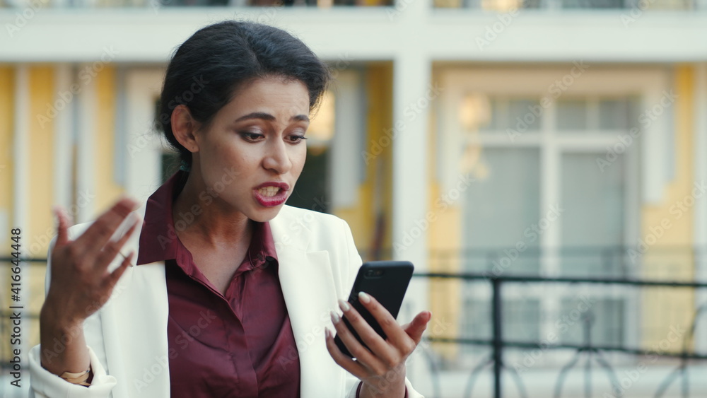 Busy mixed race woman explaining project on phone outdoors. Lady video calling Busy mixed race woman explaining project on phone outdoors. Lady video calling
