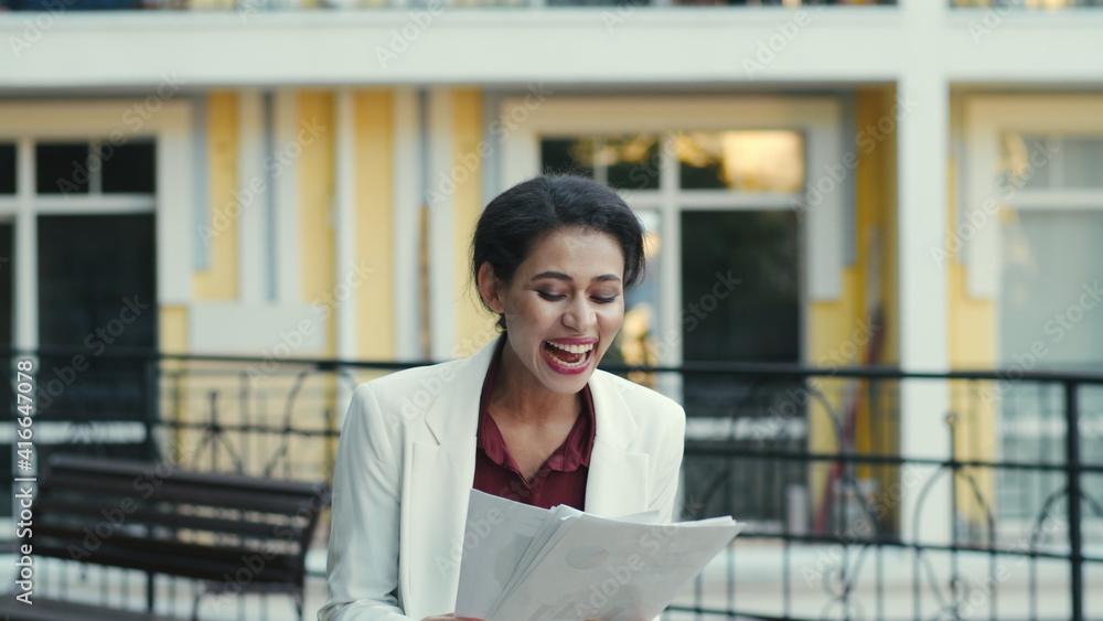Proud businesswoman examining documents outside. Woman celebrating outdoors Proud businesswoman examining documents outside. Woman celebrating outdoors