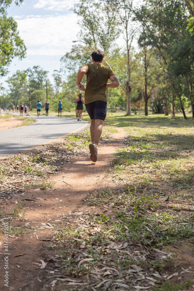 Hombre joven corriendo en sendero de arena de ñu guazu luque asunción al medio día con mucho calor entre sombras de atras Hombre joven corriendo en sendero de arena de ñu guazu luque asunción al medio día con mucho calor entre sombras de atras