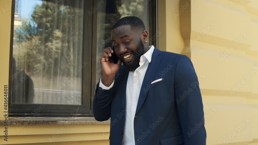 Happy african man walking on street. Young businessman talking on cellphone. Happy african man walking on street. Young businessman talking on cellphone.