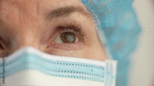 Sad and tired medic opens eyes and looking atraight at camera. Medical nurse portrait closeup. Concept exhausted health care worker. photo