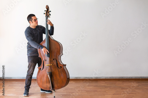 Professional double bass player. Photo shooting in studio. White background