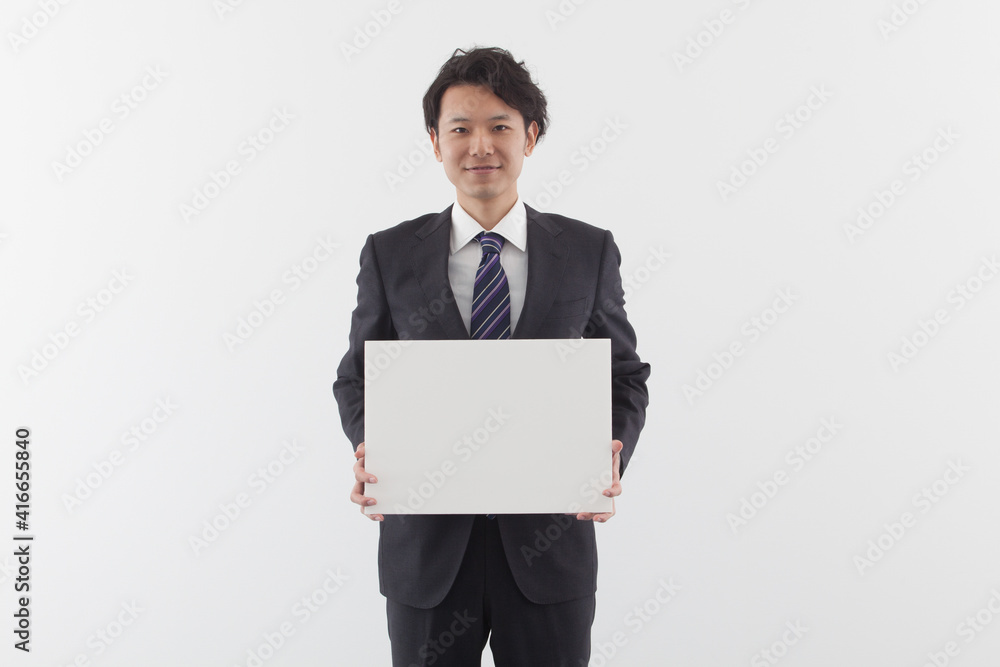 A young Asian business man holding a white board with smile A young Asian business man holding a white board with smile