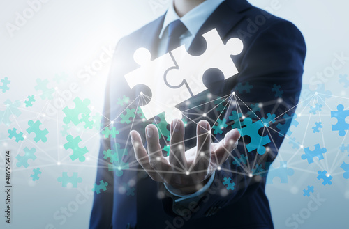 Finding business solution on internet. Businessperson connecting two jigsaw puzzle pieces.