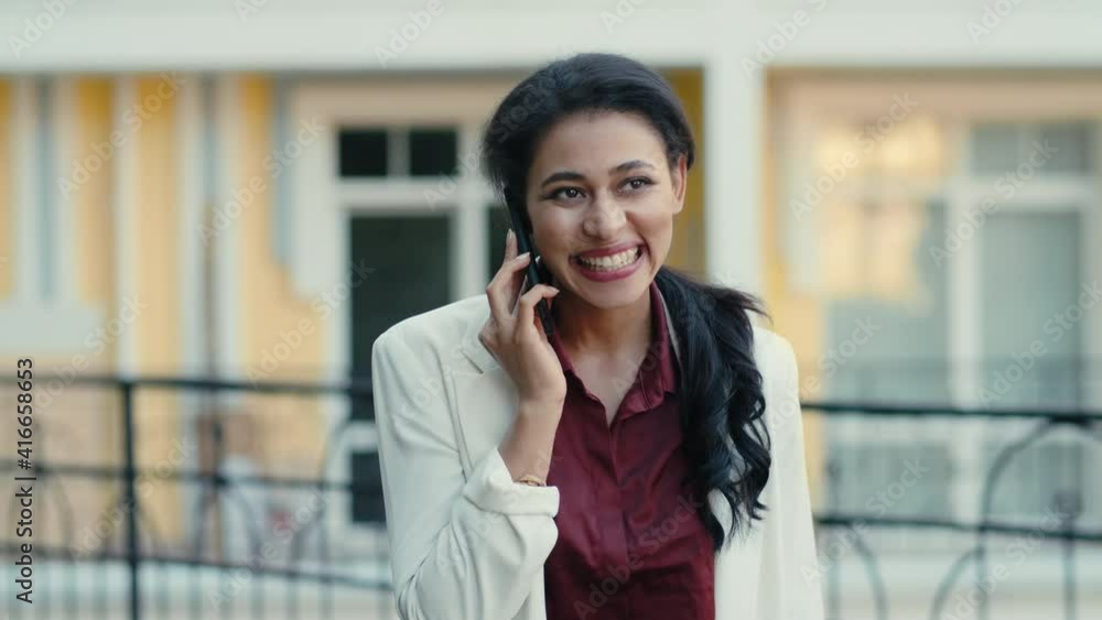 Happy mixed race businesswoman talking cellphone outside. Woman calling outdoors Happy mixed race businesswoman talking cellphone outside. Woman calling outdoors