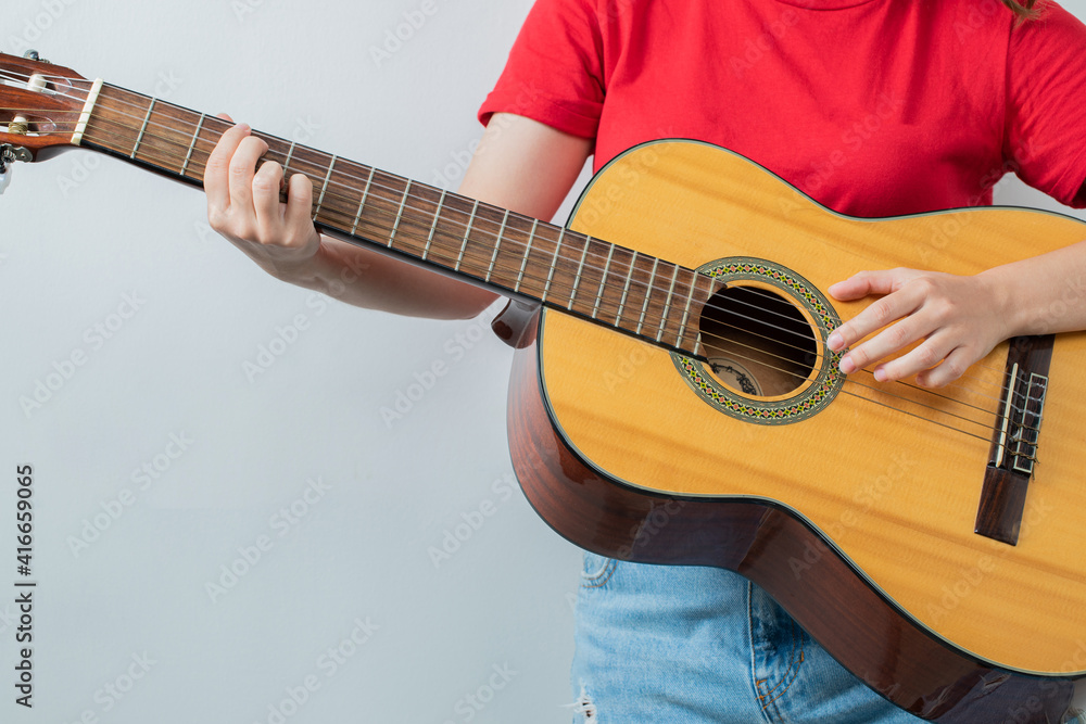 Young girl in red shirt holding an acoustic guitar