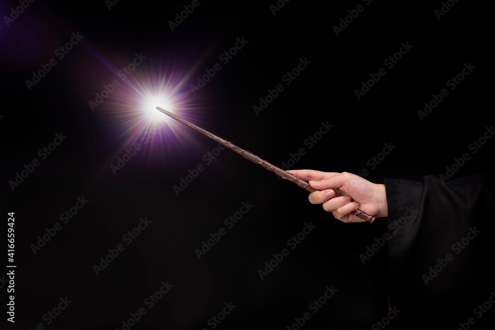 Naklejka premium Magic wand with sparkle, Miracle magical wand stick with light sparkle. Teens hand holding a wand wizard conjured up in the air.