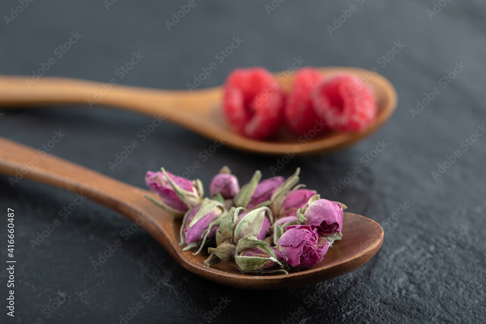 Budding roses and raspberries on wooden spoons