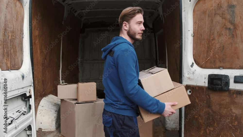 Delivery service. Man carrying boxes, parcels and putting them into white van. Urban background. Delivery service. Man carrying boxes, parcels and putting them into white van. Urban background.