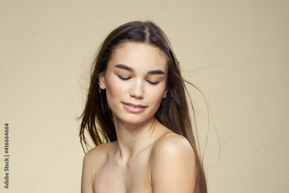 Obraz premium Pretty woman naked shoulders long hair body care beige background
