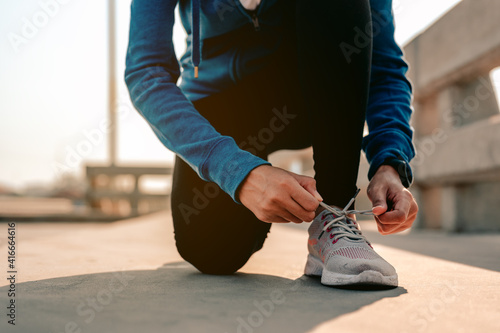 Young asian women using their hands to tie their shoes jogging in morning workout at the city. A city that lives healthy in the capital. Exercise, fitness, jogging, running, lifestyle.