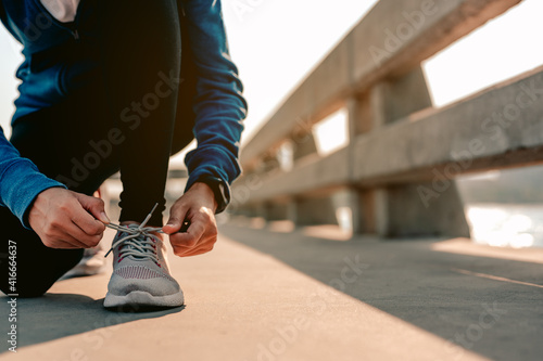 Young asian women using their hands to tie their shoes jogging in morning workout at the city. A city that lives healthy in the capital. Exercise, fitness, jogging, running, lifestyle.