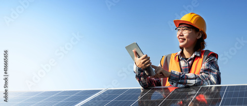 Woman engineer holding tablet with solar panel.