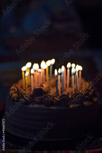 Sweet Birthday cake on a table with colors candles lighted
