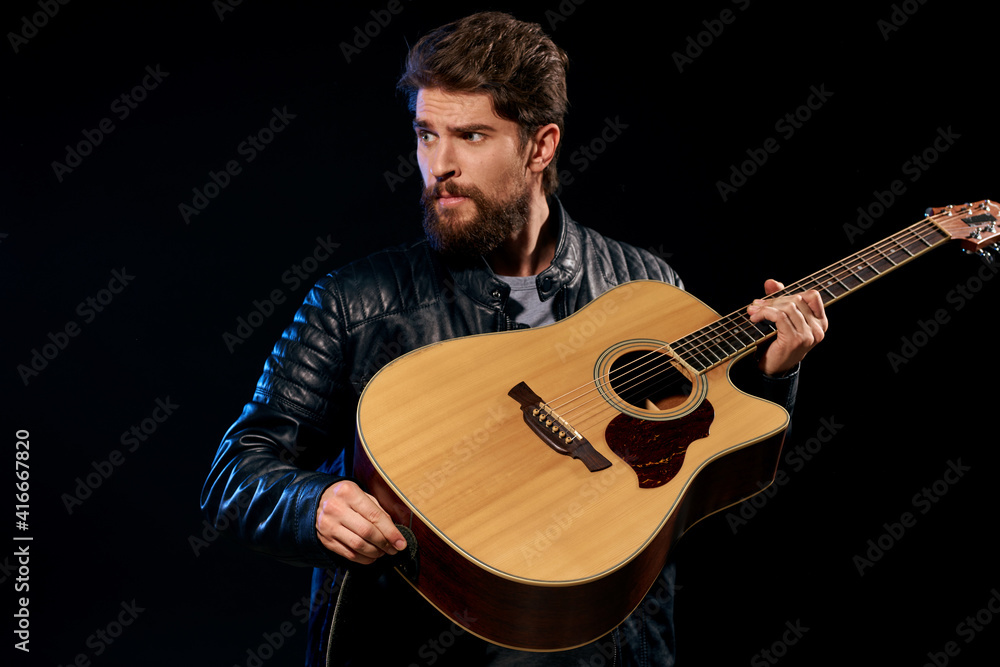 Obraz premium A man with a guitar in his hands leather jacket music performance rock star modern style dark background