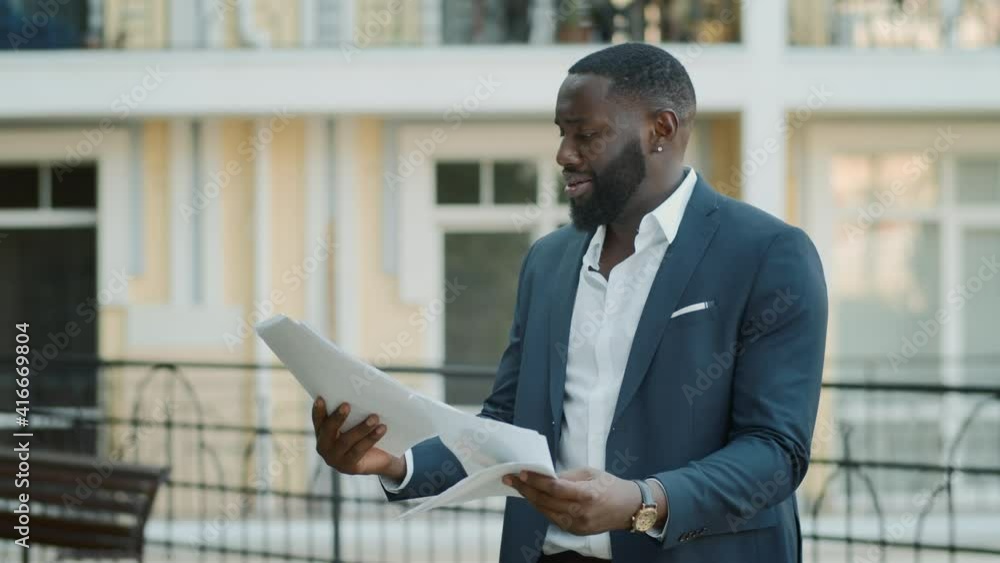 Disappointed african american business man reading documents outdoors. Disappointed african american business man reading documents outdoors.