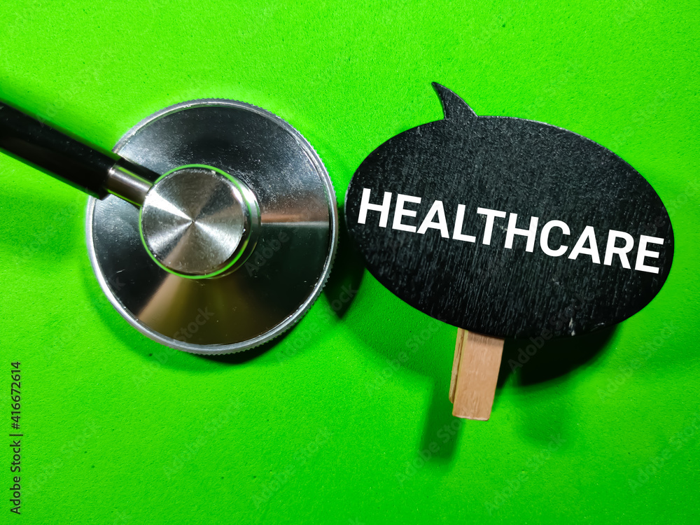 Selective focus.Word HEALTHCARE on wooden board with stethoscope on green background.Medical concept.