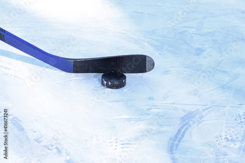 Hockey stick and puck on ice. Copy space. Selective focus. Blurred background.
