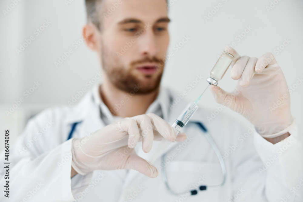 doctor in a medical gown holds a syringe in his hand and a vaccine injection. doctor in a medical gown holds a syringe in his hand and a vaccine injection.
