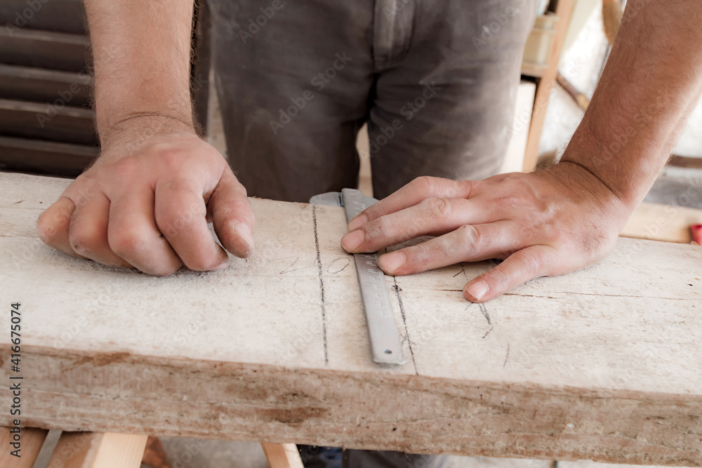 Male carpenter working with wood material in a garage. Male carpenter working with wood material in a garage.