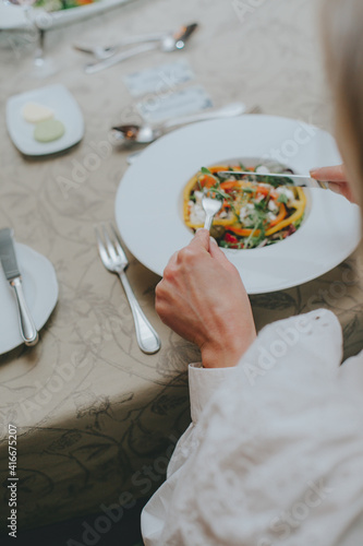 There is a salad close-up. hands properly hold cutlery in the restaurant. table etiquette.