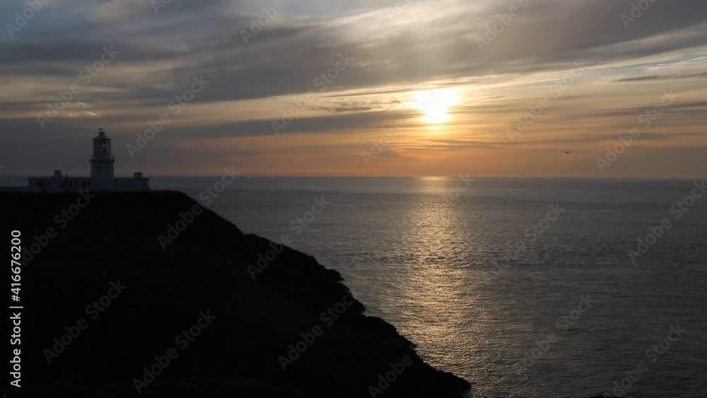 The Sun setting behind the lighthouse at Strumble Head, Pembrokeshire, Wales, UK. The Sun setting behind the lighthouse at Strumble Head, Pembrokeshire, Wales, UK.