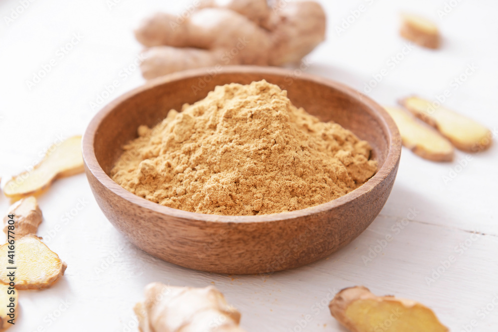 Bowl with ginger powder on light wooden background Bowl with ginger powder on light wooden background