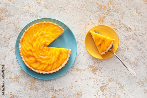 Plates with tasty mango pie on light background