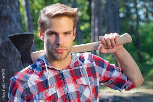 Strong man. Lumberjack on serious face carries axe on shoulder. Sexy guy.