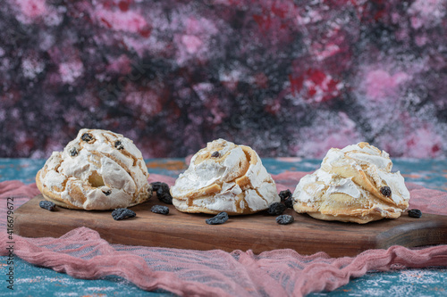 Fried meringue cookie with black raisines on a wooden board photo