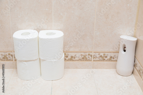 Rolls of white toilet paper and air freshener on the toilet shelf. Modern electric air freshener.
