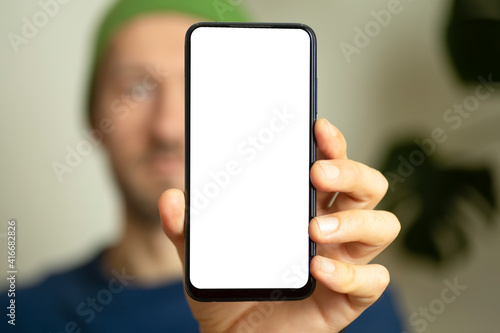 Blank smartphone screen in the hands of a young man. Man showing blank smartphone screen